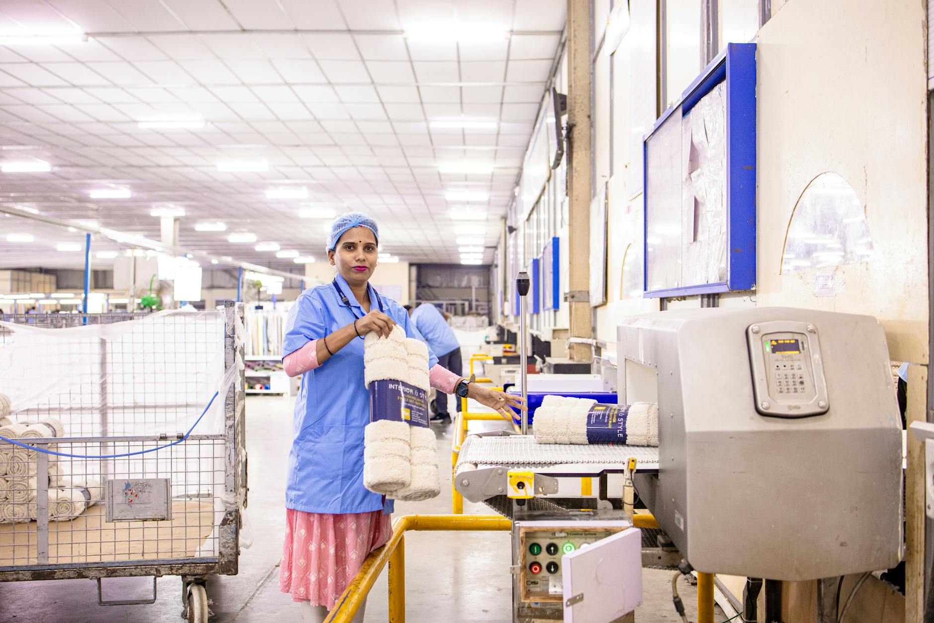 Pracownica tekstylna układa produkty na półkach w hali produkcyjnej