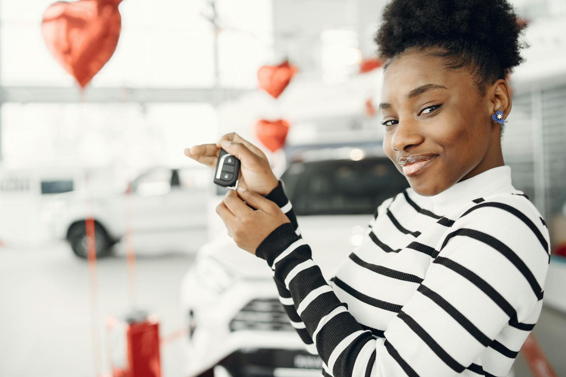 Młoda kobieta trzyma kluczyki do świeżo kupionego używanego auta