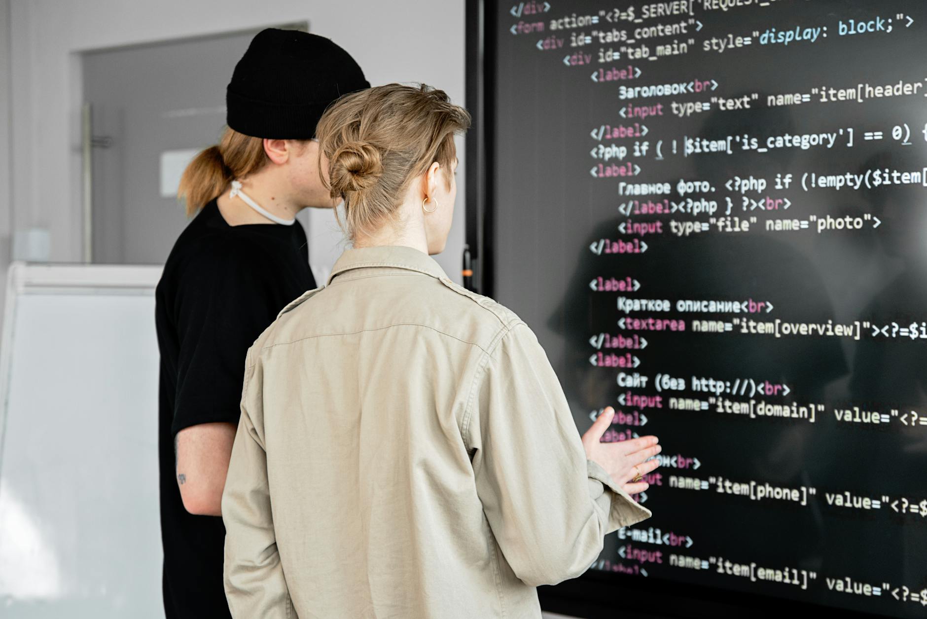 Dwóch programistów analizuje kod na dużym ekranie w nowoczesnym biurze