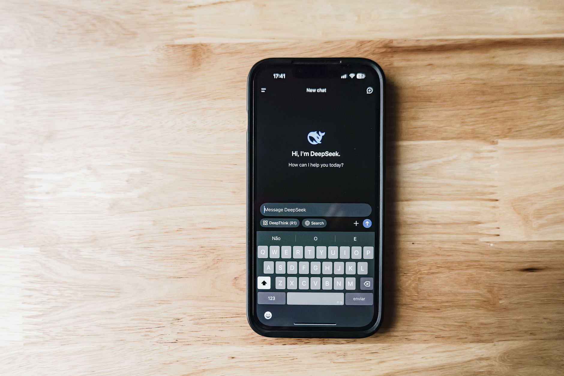 Smartfon na drewnianym stole z interfejsem czatu AI DeepSeek