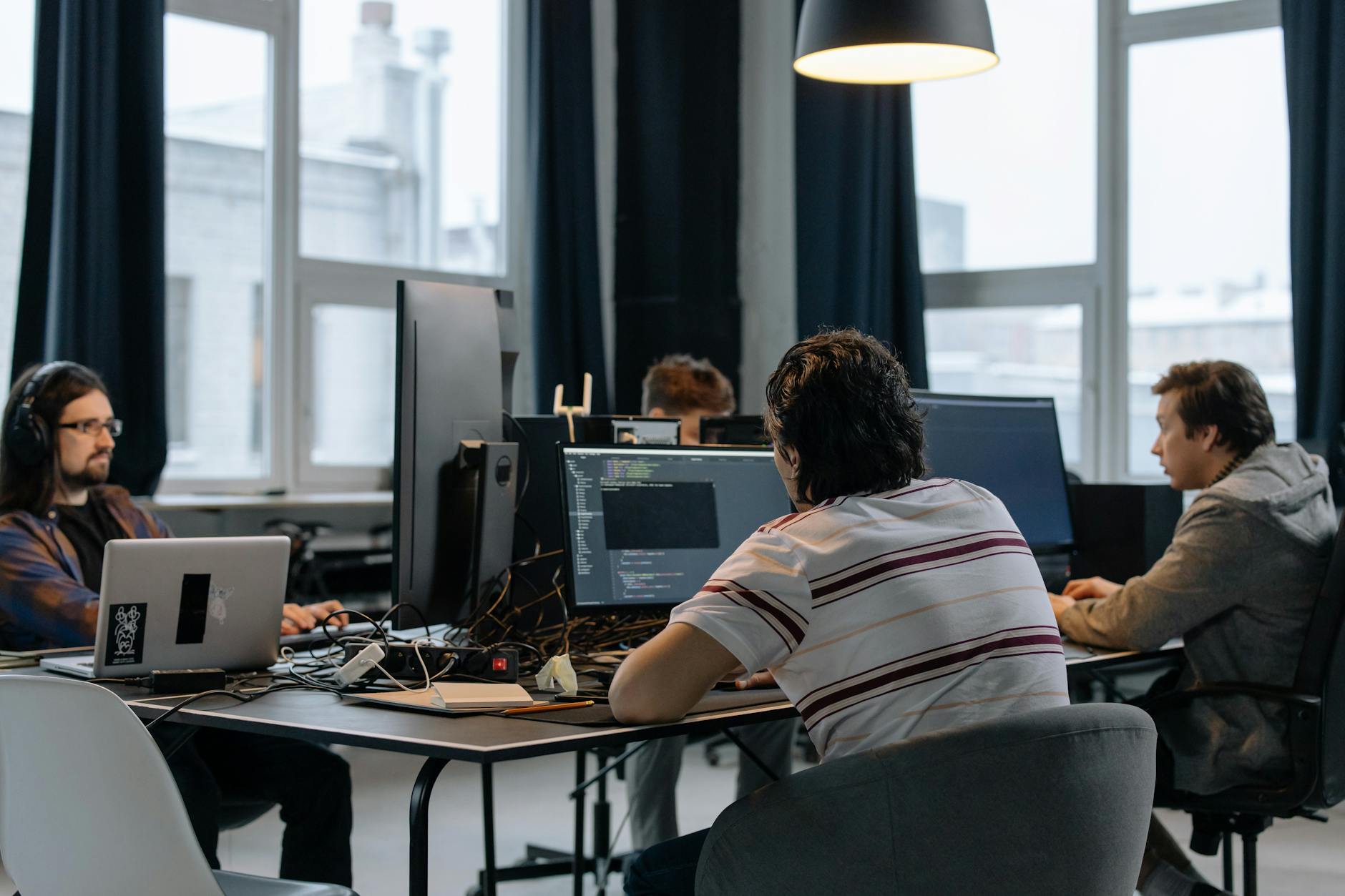 Zespół programistów pracuje wspólnie przy komputerach w nowoczesnym biurze tech
